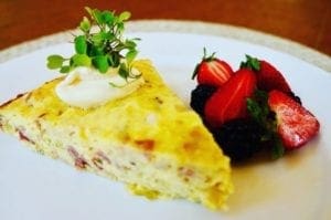 quiche on plate with strawberries at cannabis bed and breakfast